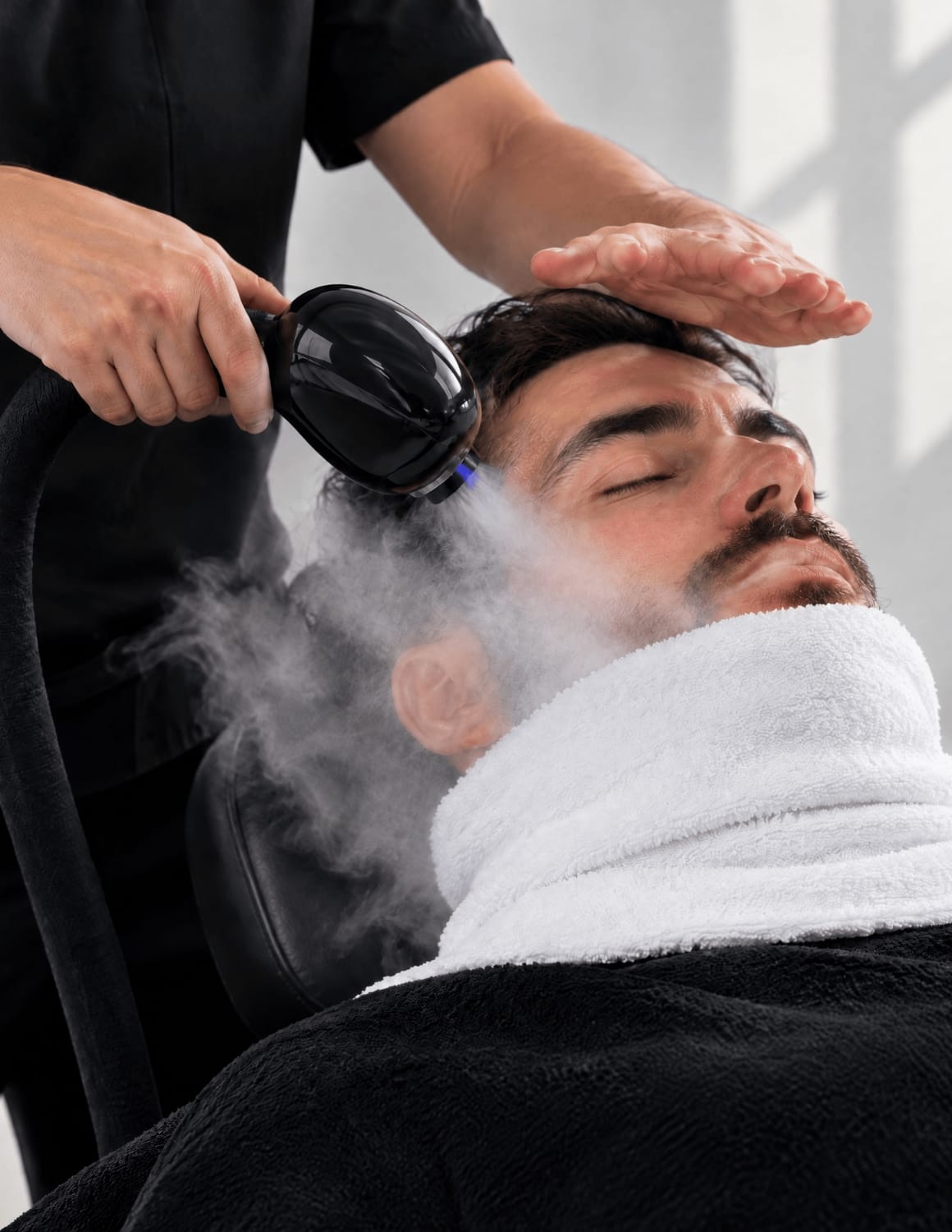 Professional face and hot-towel steam treatment with subtle Nano Blue Light before shaving
